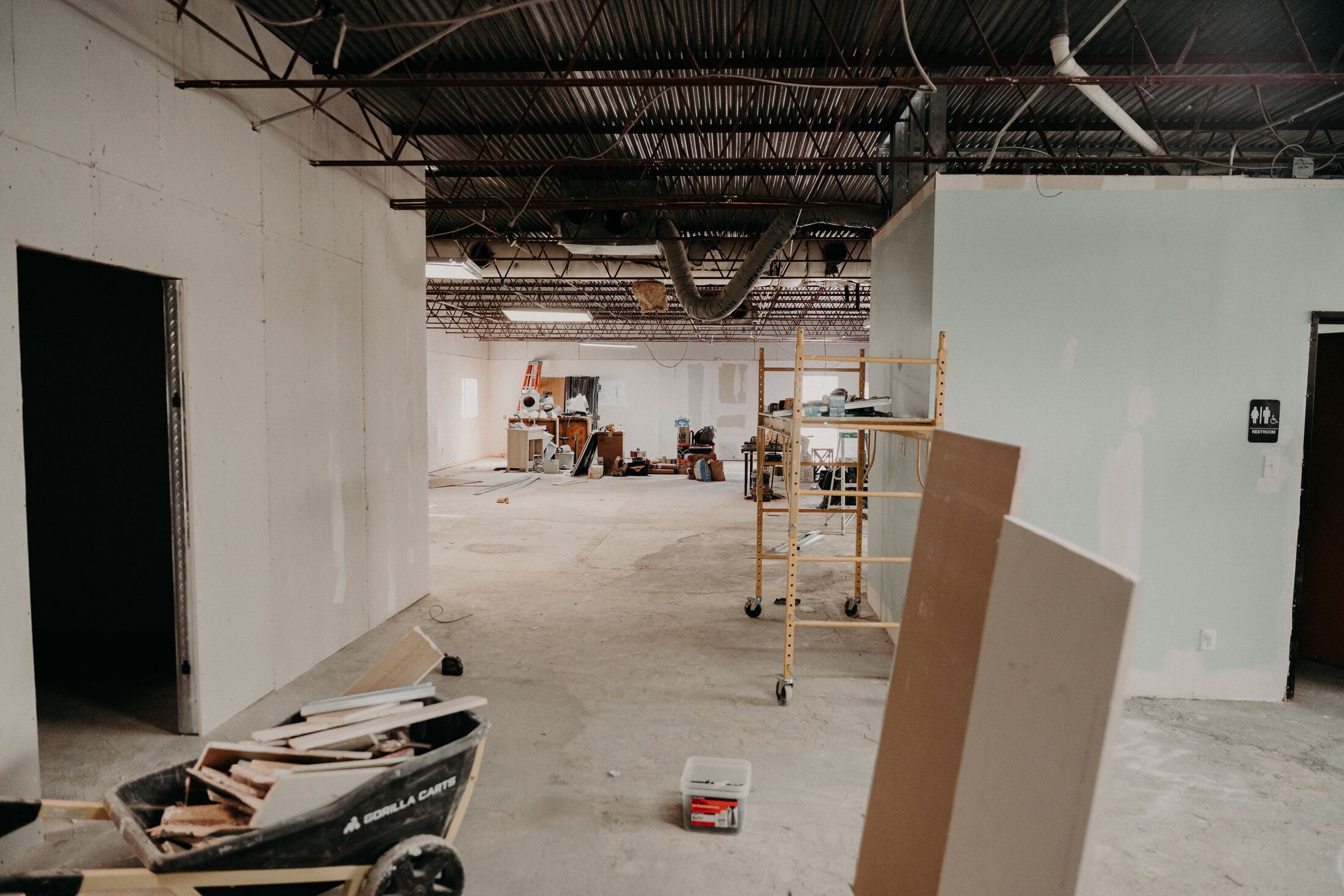 Wide view of a fully gutted suite with scaffolding and materials