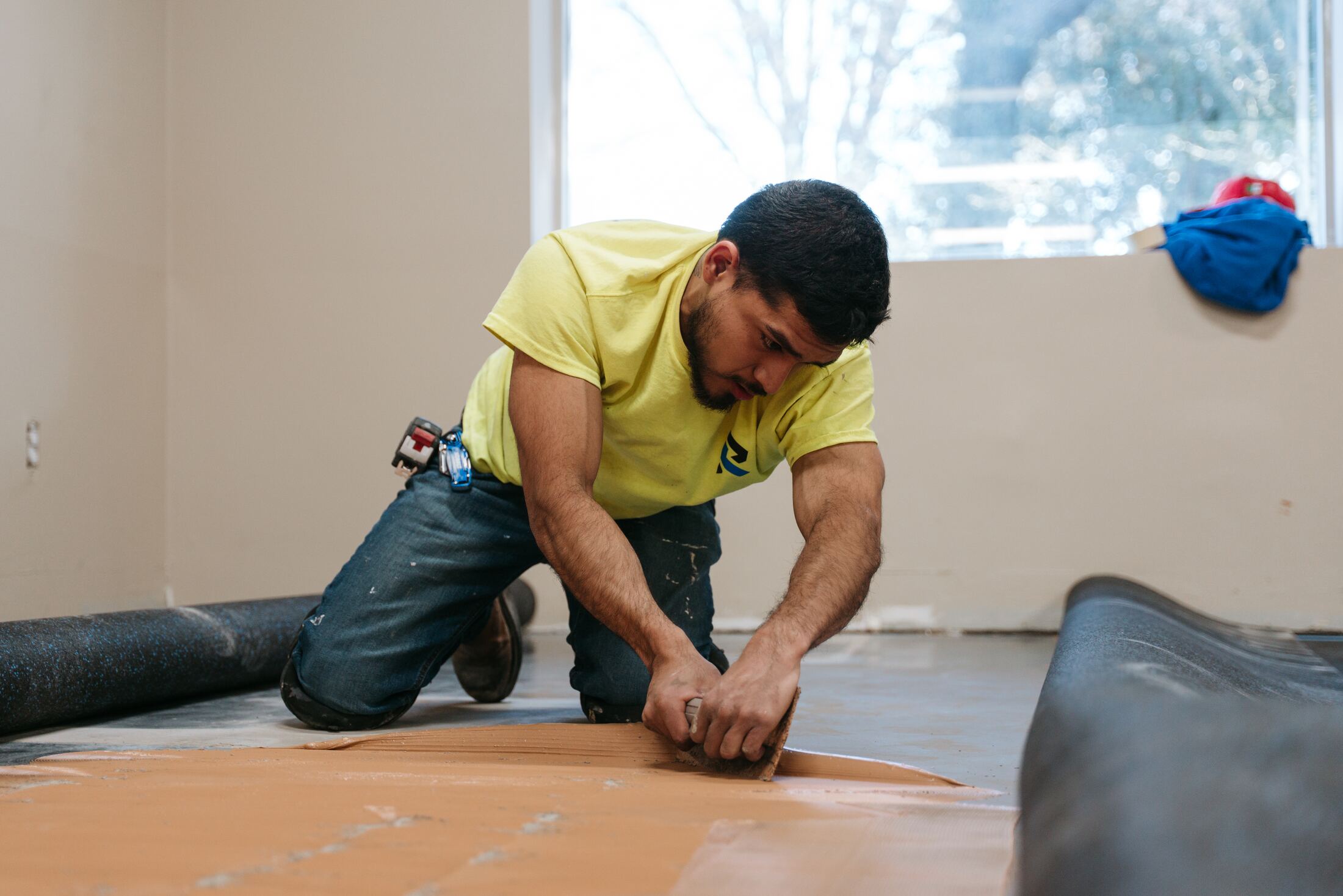 Resolver crew member spreading adhesive for the training room flooring